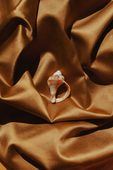 Seashell ring on a golden cloth background