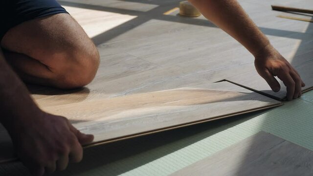Man lay laminate on the floor in the room on a green substrate.