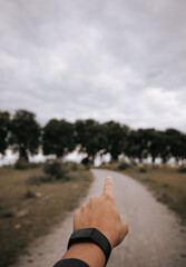 Hand pointing towards a footpath into the treeline, wanderlust, adventure and exploration