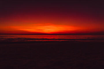Ocean beach with waves and reflection at sunset or sunrise in Bali.