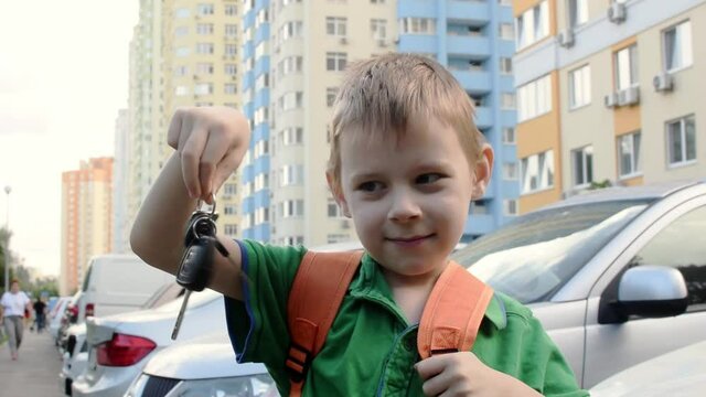 The boy is shaking the keys to a new apartment in a residential area. Acquisition of real estate, mortgage, credit.