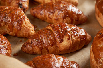 baked croissants in a baking sheet on brown parchment paper, delicious and appetizing pastries