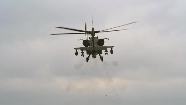 AH-64 Apache helicopter firing gun while hovering
