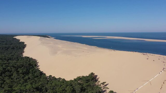 Dune du Pilat staircase with people climbing to the summit from the forest area, Aerial dolly out shot
