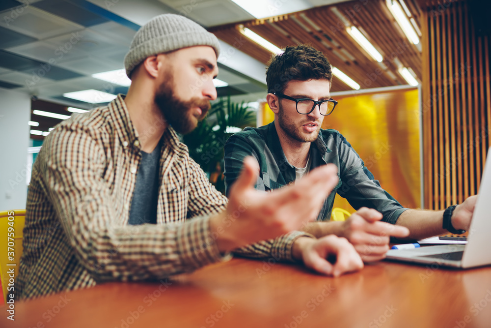 Poster two professional it developers dressed in casual wear discussing new programme during dispute at lap