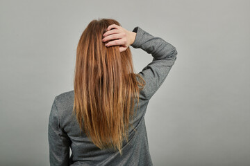 Fototapeta premium Posing with her back faced to camera, isolated over copy space background. A lovely stands. Standing. Young attractive woman, dressed gray jacket, with green eyes, light brown hair, background