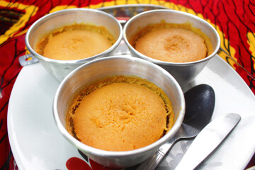 Three Metal Cups of Beans Cake or Nigerian Moi Moi served on a white plate 