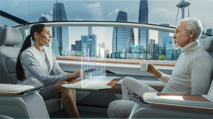 Casual Business Meeting Between Senior Male and Female inside a Futuristic Driverless Autonomous Car with Augmented Reality Presentation Interface. Self-Driving Van Driving on Downtown City Streets.