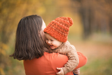 mother with child in her arms against background of autumn. family mom and baby walk in Park. kids...