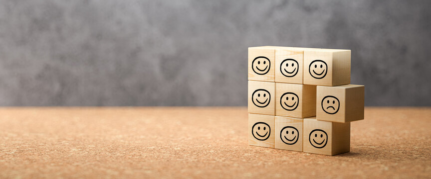 cubes with happy emoticons as a group and one unhappy one on concrete background