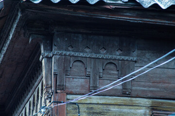 Fototapeta na wymiar Roof of an old Russian house. Carved roof of an old house. The carving on the tree. Beautiful handmade patterns