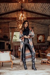 Fototapeta na wymiar Beautiful model posing for photos in a room. Wearing black pants, boot and colorful blouse.