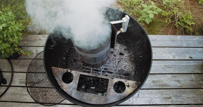 Top down shot of charcoal barbecue chimney starter smoking as paper burns
