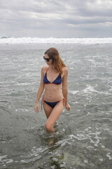 Portrait of a brunette caucasian woman in blue bikini on the beach.