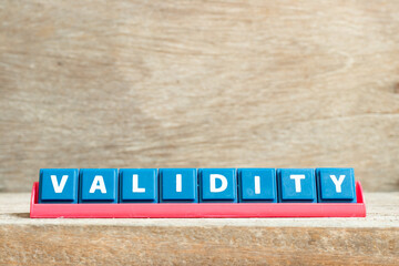 Tile letter on red rack in word validity on wood background