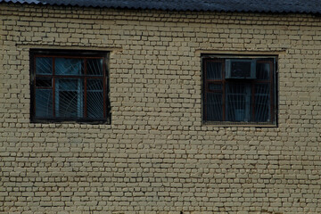 An old wooden window on an old yellow brick wall, a window with bars