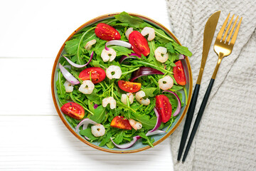 Mediterranean diet menu concept Healthy salad of fresh vegetables - tomatoes, arugula, purple onions, shrimps, soy sauce and sesame seeds in plate on white wooden table Vegan food Flat lay Top view
