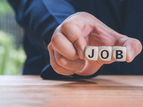 Closeup of businessman's giving wooden block written JOB text to candidate or applicants for hiring. Jobs search and employment concept.