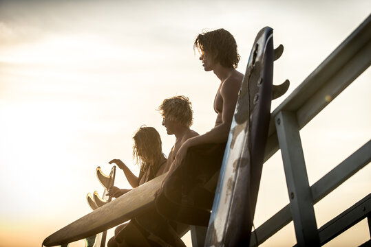 Three surfers relaxing on the beach after sport