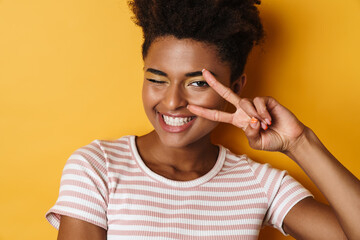 Image of african american woman gesturing peace sign and winking