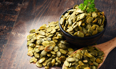 Composition with bowl of pumpkin seeds on wooden table
