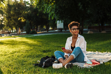 African woman sitting outdoors in park on a grass