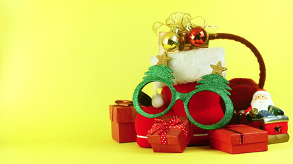 Green glitter fancy eyeglasses on red boot and santa claus model decorate with red christmas gift boxes, have space for idea.