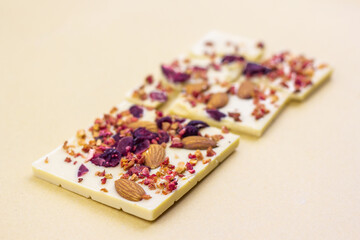 A broken bar of white chocolate with dried berries, candied fruits and almonds.