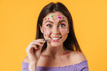 Image of joyful woman with stickers on face and flower in her mouth