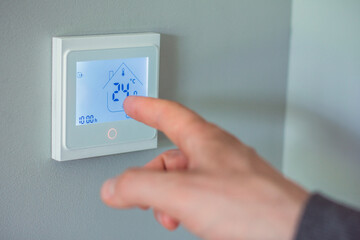 Image of a man's hand turning off a home thermometer.