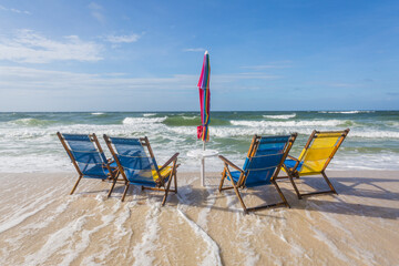 Four empty beach chairs being overtaken by incoming tide