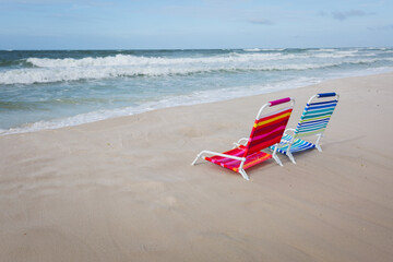 Fototapeta na wymiar Two empty beach chairs facing the ocean