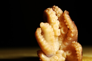 A delicious octopus prepared to be cooked in a gray bowl on a black background. Horizontal format.