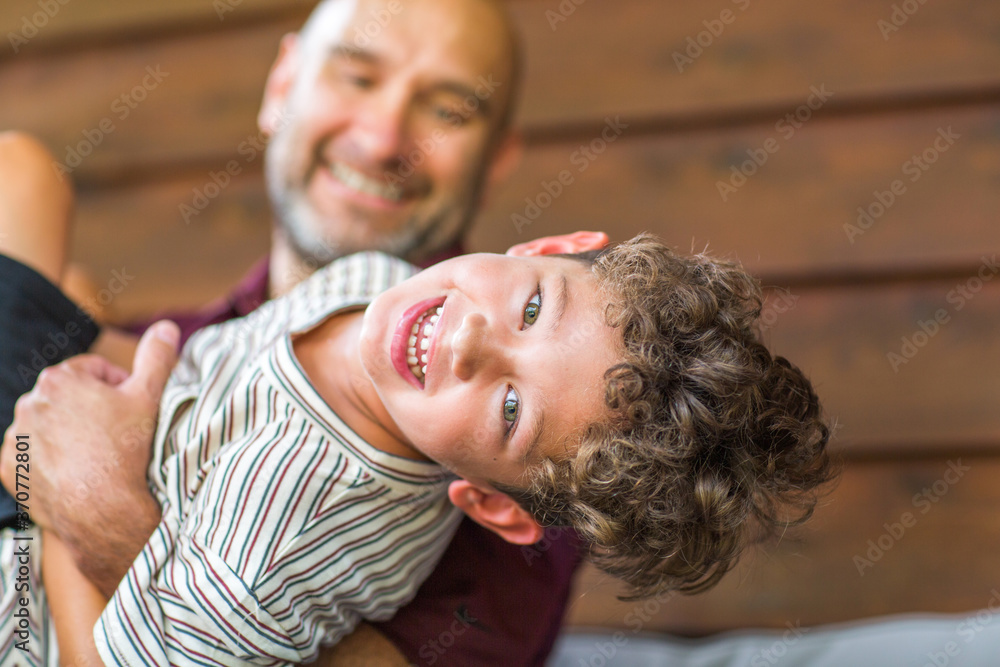 Wall mural Hispanic father sitting and hugging his son.