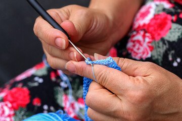 Hands of a needlewoman crochet. Female fingers knit a toy.