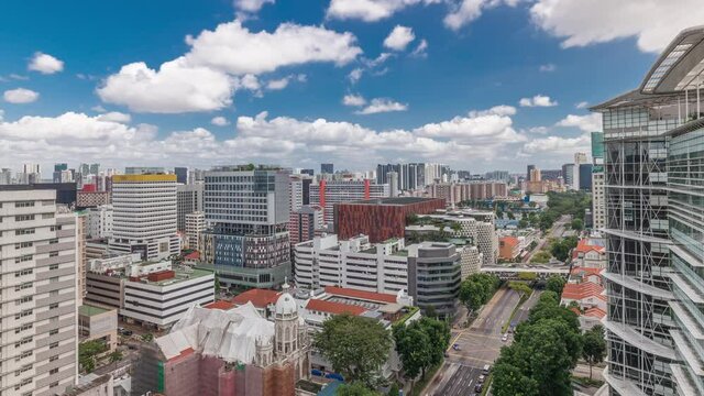 Singapore skyline with Victoria street and National Library aerial timelapse. Green trees on the road with traffic. Clouds on a blue sky