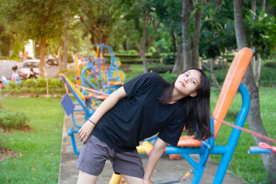 soft sunlight image of a portrait young Asian woman in black shirts warming up before exercising outdoors in a park, exercise area.