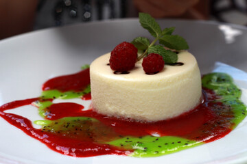 Cheesecake with fresh raspberries. Cottage cheese dessert with raspberry jam and kiwi on a white plate.