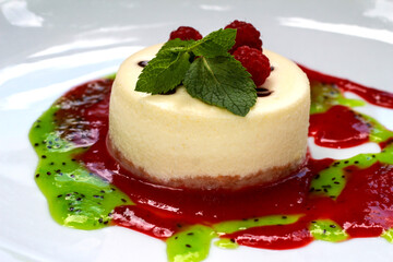 Cheesecake with fresh raspberries. Cottage cheese dessert with raspberry jam and kiwi on a white plate.