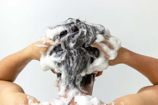A man washes his head with shampoo on white background