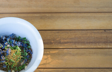 Lavender bloom, cinnamon powder, and mint leaves in a white bowl with wood background and space  for text