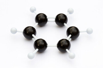 Plastic ball-and-stick model of a benzene molecule (C6H6) on a white background. The molecule is...