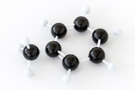 Plastic ball-and-stick model of a toluene or methylbenzene molecule (C7H8), shown with kekule structure on a white background. Methyl group left.