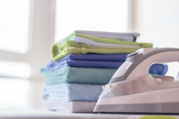 Ironing and stack of towels on the ironing board close up background.