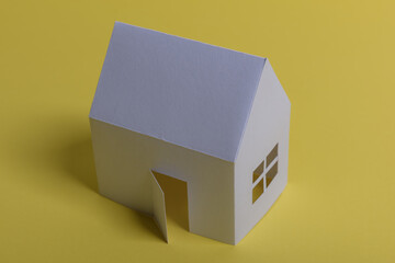 White family paper house, house projects plan and blueprints in the background. Minimalistic and simple concept, style. Horizontal orientation. View from above