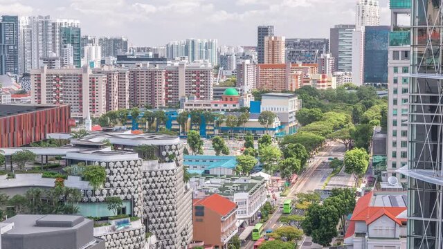 Singapore skyline with Victoria street and National Library aerial timelapse. Green trees on the road with traffic. Clouds on a blue sky