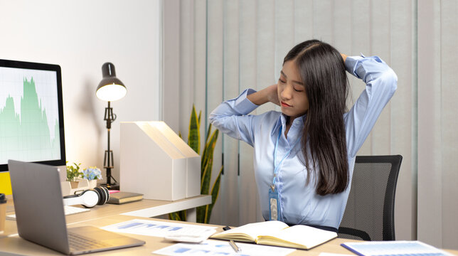 Asian Woman Stretches Lazily After Working In The Office And Completing Overtime.