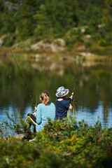 A young girl with her little brother fishes in a small lake.  Shot in the deep wild forest of...