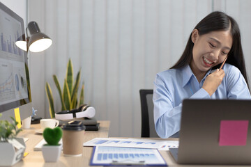 Young Asian woman typing and talking on the phone at the same time.