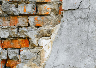 The texture of an old, destroyed wall and a building made of red, orange uneven bricks with cracks, gray cement and concrete. Photography, abstraction, background.